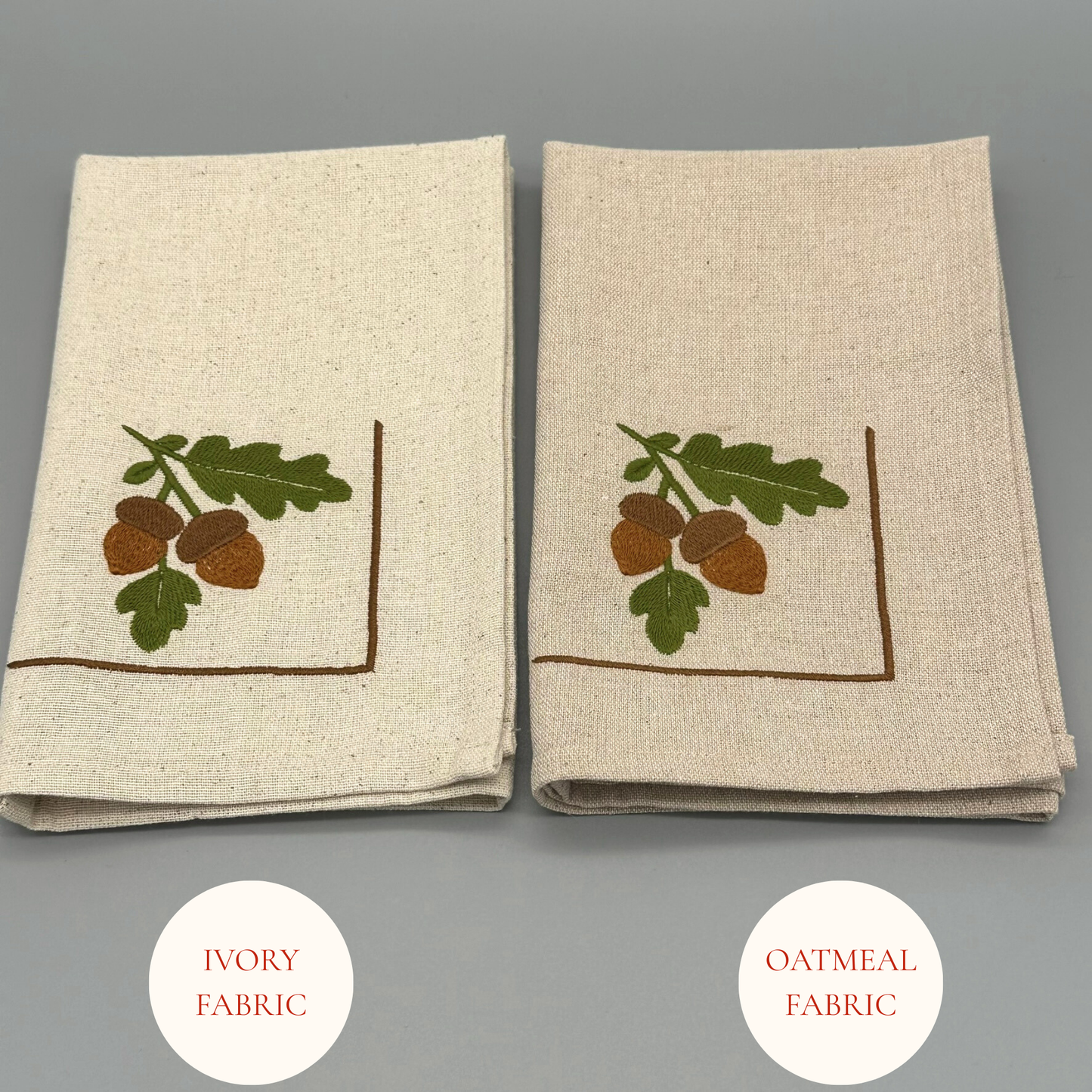 Two folded napkins with embroidered acorn and leaf design 