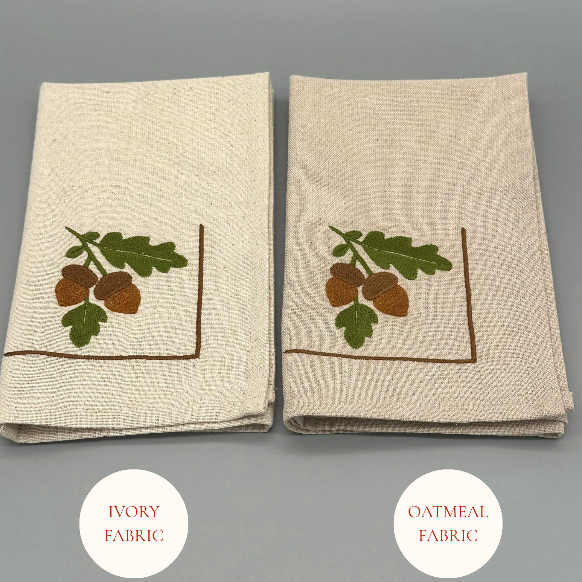 Two folded napkins with embroidered acorn and leaf design 