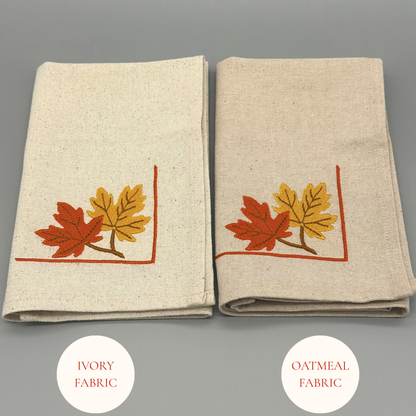 Two folded napkins with embroidered autumn leaf design