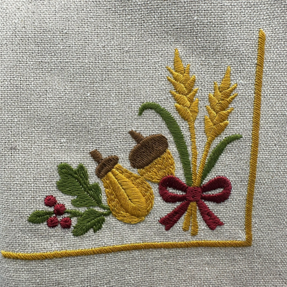 Embroidered design of oak leaves, acorns, and wheat, ribbon on napkin