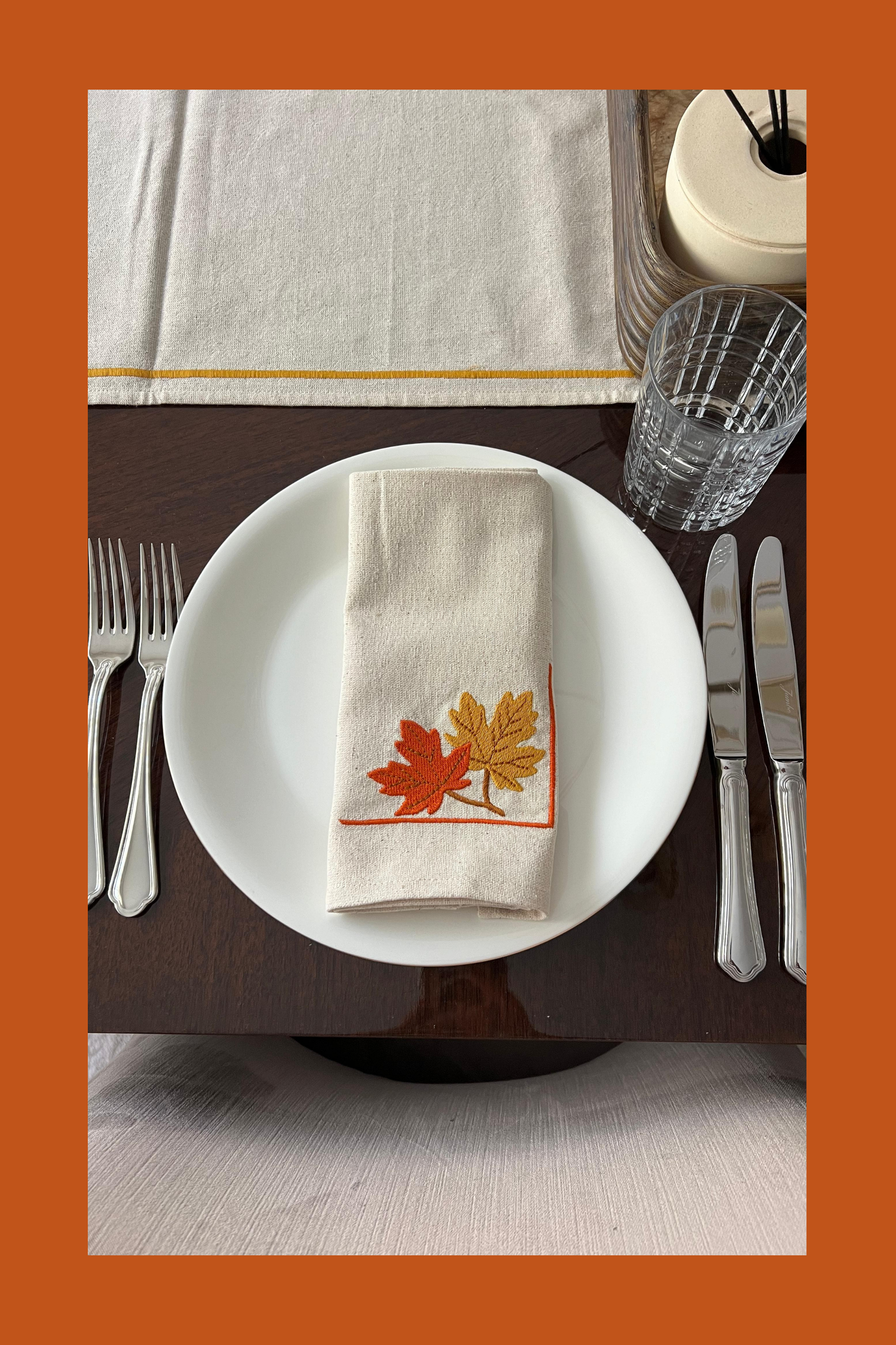 Table setting with a decorative napkin featuring embroidered autumn leaves
