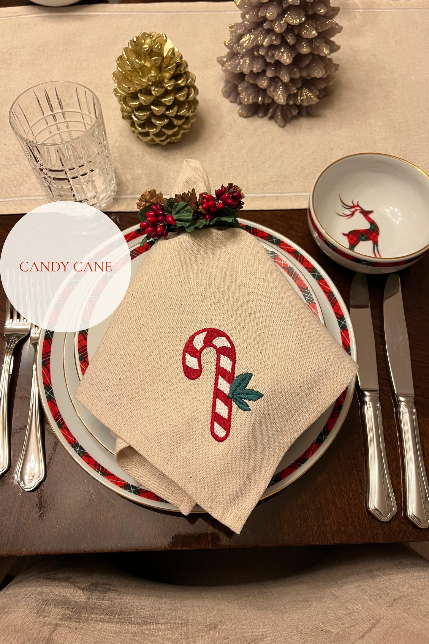 Christmas-themed table setting with candy cane design embroidered on napkin.