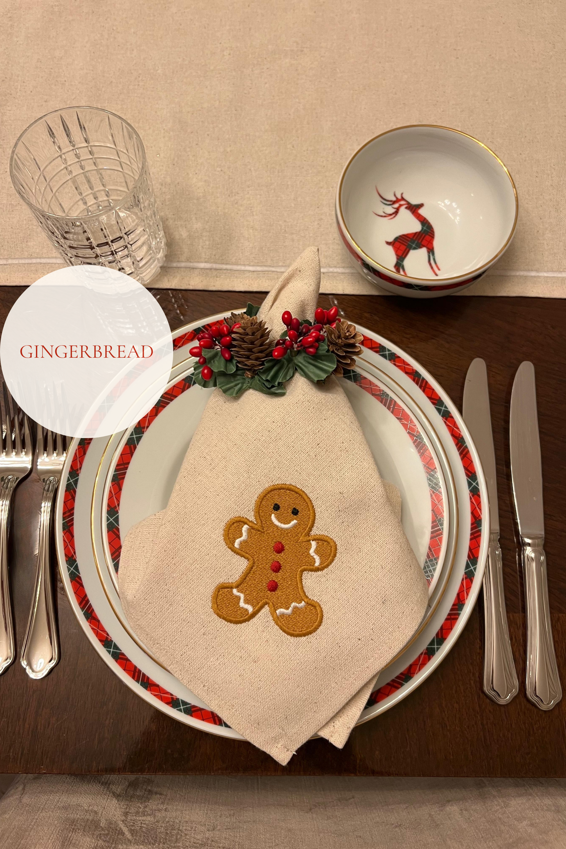 Christmas-themed table setting with gingerbread napkin and decorative plate.