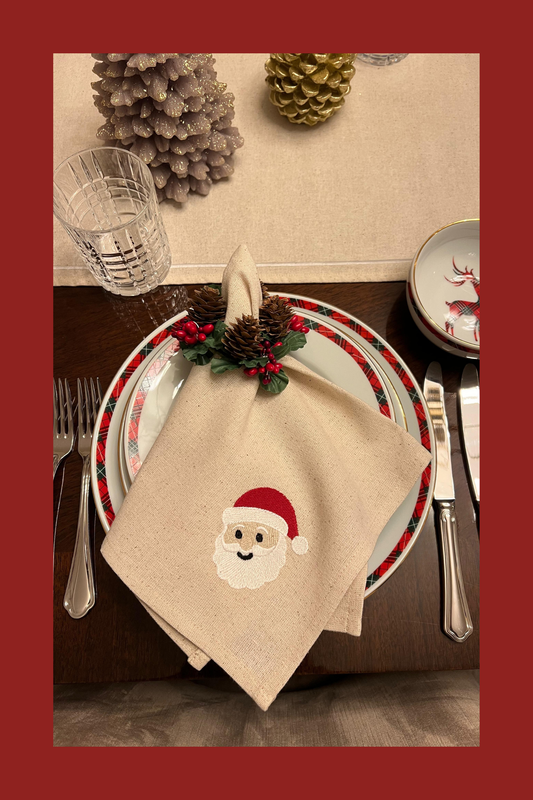 Christmas-themed table setting with a embroidered napkin featuring a Santa face design.