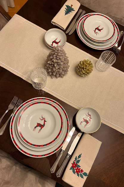 Christmas-themed table setting with poinsettia and Christmas tree embroidered napkins