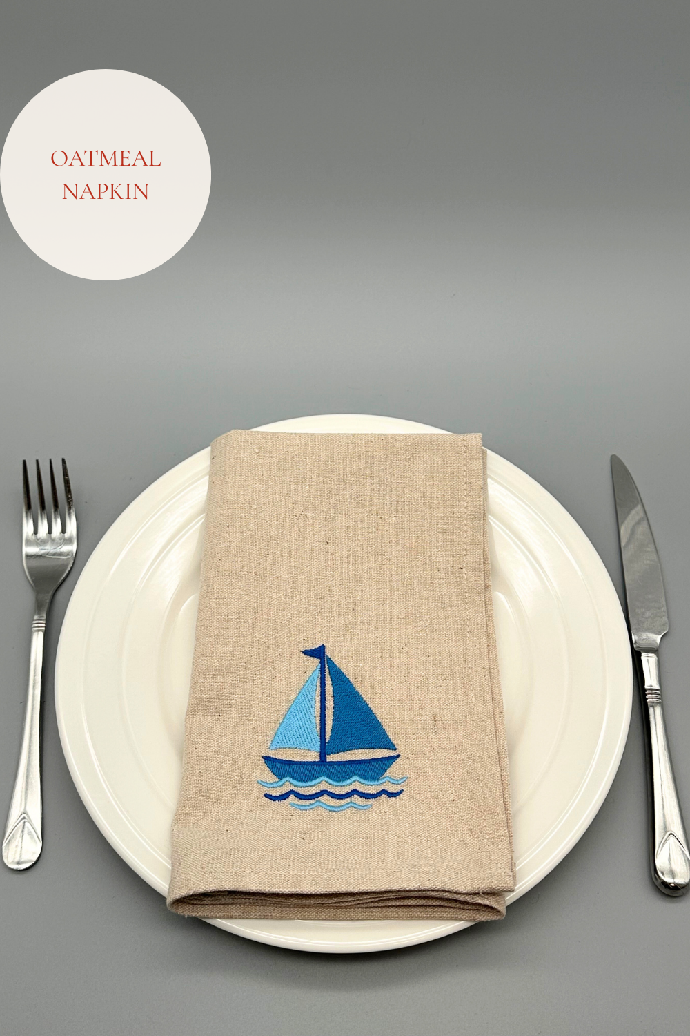 Oatmeal napkin with an embroidered blue sailboat