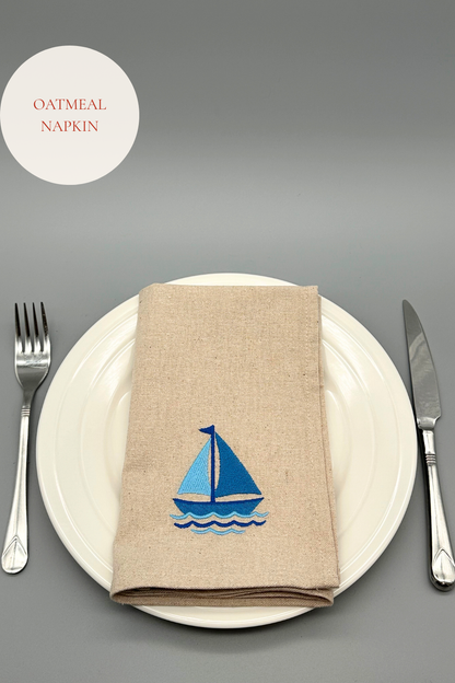 Oatmeal napkin with an embroidered blue sailboat