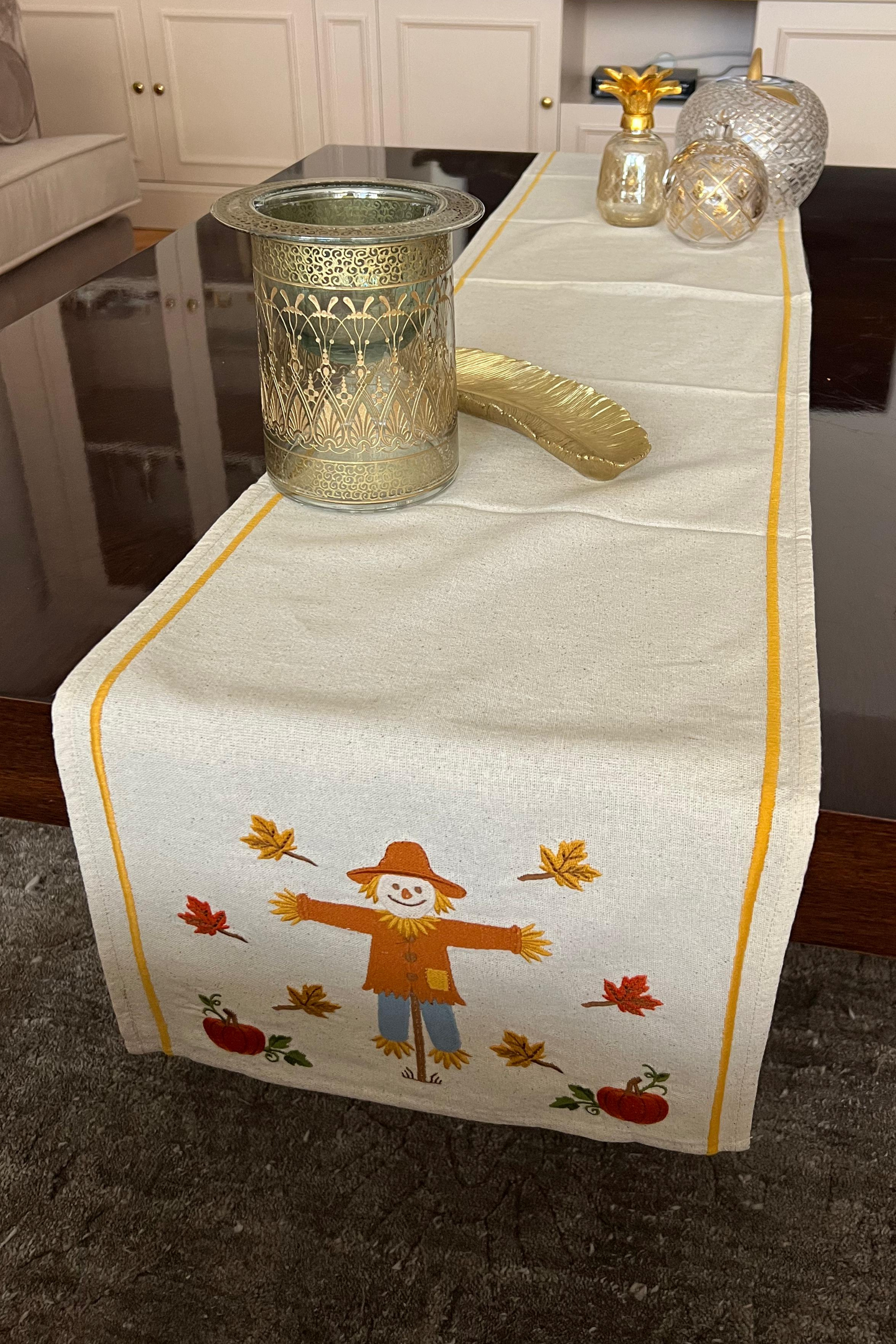 Table runner with scarecrow design on a table in a living room setting