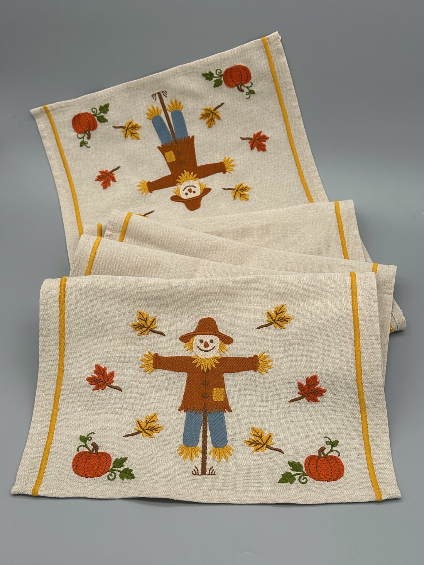 Embroidered table runner with scarecrow and autumn design.